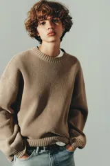 Jersey de punto liso con diseño oversize, cuello redondo y manga larga con puños acanalados.