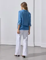 Camisa celeste de lyocell, con cuello a la base, escote en V y abertura central con botones. Tiene bolsillos aplicados en la parte delantera y mangas 3/4 regulables con presilla y botón.