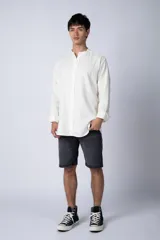 Camisa de lino color blanco roto, de manga larga y corte recto, con cuello mao y cierre frontal de botones.
