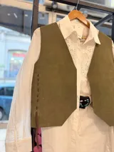 Chaleco artesanal confeccionado en cuero, con diseño de cordones decorativos en el frente y terminaciones rústicas.