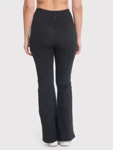 Calza negra de tiro alto, corte ajustado en la parte superior y acampanado en la parte inferior, con aberturas en los tobillos.