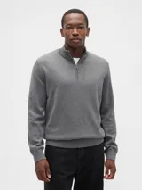 Buzo de tejido de punto color negro, con cuello alto y cierre frontal parcial. Presenta puños y ruedo acanalados.