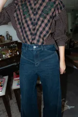 Blusa de algodón con estampado a cuadros en tonos azul y negro, con bordados decorativos en color bordó sobre el canesú. Presenta cierre frontal con botones, cuello redondo y mangas largas levemente abullonadas.