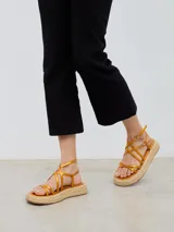 Sandalias con plataforma de esparto, tiras cruzadas color naranja y cierre con hebilla al tobillo.