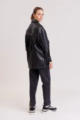 Campera negra simil cuero con flecos en el frente, cuello clásico, cierre con botones a presión y corte holgado.