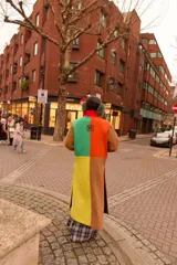 Tapado largo de paño con diseño color block en tonos marrón, verde, amarillo y naranja. Presenta solapas, bolsillos de parche en contraste rosa y un corte recto.