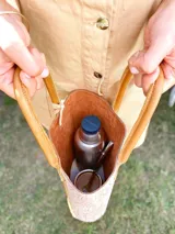 Bolso matero de cuero color chocolate con textura croco, asas cortas y detalle de costuras en los laterales. Incluye un dije con flecos en tonos beige y negro.