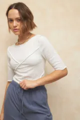 Remera negra de manga tres cuartos, escote redondo y detalle de costuras superpuestas de forma asimétrica.