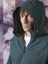 Campera verde oscuro con capucha, cierre frontal y bolsillos laterales.