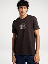 Camiseta de corte regular color marrón oscuro, con cuello redondo, mangas cortas y estampa gráfica central en color blanco con diseño de un café.