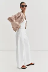 Chaqueta estilo bomber de punto color beige con acabado brillante, cuello redondo, manga larga con puños elásticos y cierre frontal con cremallera.