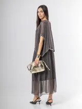 Vestido largo de seda italiana en color gris oscuro, con falda larga lisa, forro y cintura elastizada. Posee una sobrecapa con detalles de paillettes en los bordes de las mangas y la cintura.