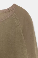 Jersey de punto color marrón topo, de manga larga y corte recto, con cuello redondo ribeteado con hilo brillante.