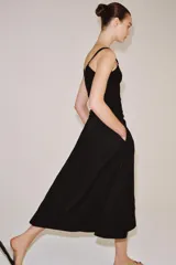 Falda midi de tiro medio color negro, con cintura elástica, bolsillos laterales ocultos y bajo con acabado en línea evasé.