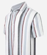 Camisa de hombre de manga corta con cuello tradicional y abotonado frontal. Presenta un tejido texturizado con un patrón de rayas verticales en tonos beige, blanco y marrón claro.