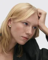 Par de aros pequeños con perlas blancas y borde dorado.