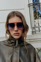 Cazadora estilo bomber color marrón oscuro, con efecto piel, cuello subido y manga larga. Tiene bolsillos delanteros con cierre de cremallera y acabados elásticos en puños y bajo. El cierre frontal es con cremallera y botones a presión ocultos.