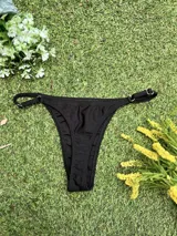 Conjunto de bikini negro con corpiño tipo top y bombacha colaless regulable, confeccionado en tela metalizada.