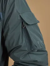 Campera de abrigo azul marino con capucha, cierre frontal con botones y cremallera, múltiples bolsillos y forro interior naranja.