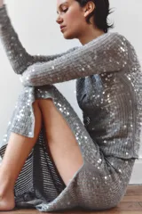 Falda midi de punto semitransparente con aplicación de lentejuelas a tono e hilo metalizado. Presenta tiro alto, cintura elástica y abertura lateral en el bajo.