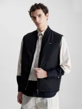 Chaleco negro acolchado con cuello alzado, cierre de cremallera, bolsillos con botón a presión y logo de Calvin Klein en el pecho.