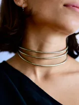 Gargantilla rígida de diseño minimalista compuesta por tres aros metálicos superpuestos en tono plateado.