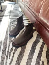 Bota Chelsea de cuero color marrón chocolate con elástico lateral negro y suela track color negro.