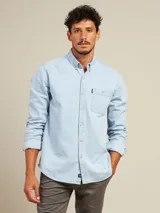 Camisa celeste de manga larga con cuello abotonado y bolsillo en el pecho.