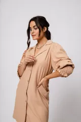 Vestido corto color tostado, con cuello solapa, abotonado al frente y mangas 3/4 con puños fruncidos.