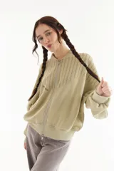 Campera estilo bomber de algodón color verde militar, con cierre frontal de doble cursor, cuello, puños y ruedo tejidos en rib. Presenta detalles de costuras decorativas superiores y bordado en el pecho.