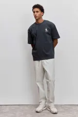 Remera de algodón color gris oscuro, de corte holgado y manga corta, con un pequeño estampado gráfico en el pecho.