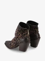 Bota corta de gamuza con estampado animal print de leopardo en tonos marrones y negros. Presenta un taco cuadrado alto y cierre posterior con tirador metálico.