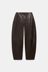Pantalón de tiro medio con diseño tipo balloon, confeccionado en tejido efecto piel. Presenta bolsillos laterales, pespuntes marcados a tono y cierre frontal con cremallera, botón y gancho metálico.