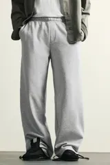 Pantalón jogger de corte relajado y pernera ancha, confeccionado en tejido de algodón con interior perchado. Cuenta con cintura elástica ajustable mediante cordón interior, bolsillos laterales y un bolsillo trasero de plastrón.