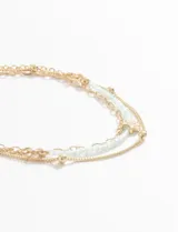 Set de tres pulseras doradas con diferentes diseños: una de cadena con bolitas, otra de cordón trenzado celeste y una tercera de cadena con dije de estrella.