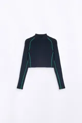 Top cropped de manga larga, cuello alto y color azul marino oscuro. Presenta costuras de ribete en color verde brillante a lo largo de los hombros, mangas y costados. Tiene un pequeño logo en relieve en el pecho.