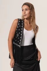 Chaleco negro de gamuza con flecos y bordados blancos en la parte frontal.