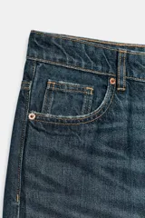 Jeans de tiro medio con corte relajado y diseño de cinco bolsillos. Presenta trabillas en la cintura, cierre frontal con cremallera y botón metálico, con un acabado de lavado desgastado.