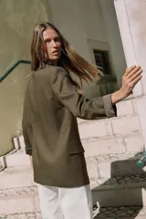 Blazer de lino color verde militar, con cuello solapa, hombreras y manga larga con puño revuelto con detalle a rayas. Cuenta con cierre frontal de un botón y bolsillos delanteros con solapa.