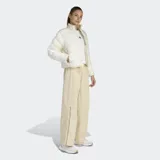 Campera puffer Adidas de corte holgado, color blanco, con cierre frontal, cuello alto y puños elásticos. Presenta el diseño icónico de las tres tiras en las mangas y tecnología Climawarm para aislamiento térmico.