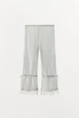 Pantalón capri de tiro medio con cintura elástica, confeccionado en tejido de viscosa con estampado de rayas verticales. Presenta un diseño de bajo ajustable mediante lazadas laterales y detalle de encaje en el ruedo.