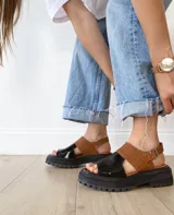 Sandalias de cuero color negro y camel, con plataforma track y hebilla ajustable.