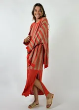 Vestido largo tejido a crochet, con rayas verticales color naranja y beige, sin mangas y con aberturas laterales.