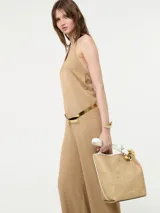 Mono color beige con escote halter, corte holgado, cinturón dorado y pantalones palazzo.