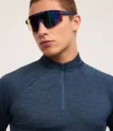 Remera deportiva térmica de hombre, color azul melange, de manga larga con corte raglán, cuello alto y cierre frontal parcial.