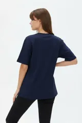 Remera de algodón negra con cuello redondo y mangas cortas, de corte holgado. Presenta estampado frontal en tonos de verde con la inscripción 'New York City Brooklyn' y el logo 'NY' rodeado de laureles.