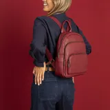 Mochila de tamaño mediano confeccionada en símil cuero color beige, con doble bolsillo frontal con cierre metálico, asa de mano superior y correas regulables de cinta tejida.