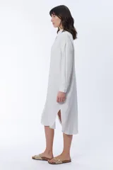 Vestido camisero blanco de lino, corte oversize, con cuello camisero, mangas largas y cierre frontal con botones.