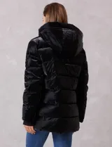 Campera puffer de acabado satinado en color negro, con diseño capitoneado horizontal. Cuenta con cierre frontal metálico, capucha fija con interior de piel sintética y bolsillos laterales con cierre. Incluye puños internos de tejido elastizado con abertura para el pulgar y logo metálico en la manga.
