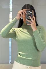 Buzo de tejido de punto fino en color verde, con cuello medio y mangas largas, de corte ajustado al cuerpo.